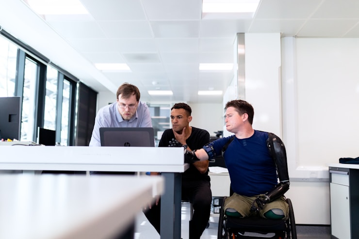 Engineers look at computer screen with prosthetic limb user