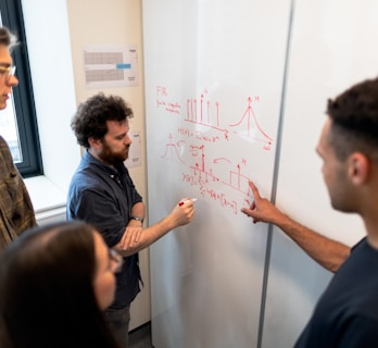 man in black crew neck t-shirt writing on white board