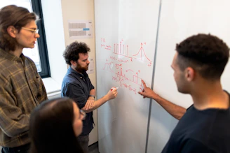 man in black crew neck t-shirt writing on white board