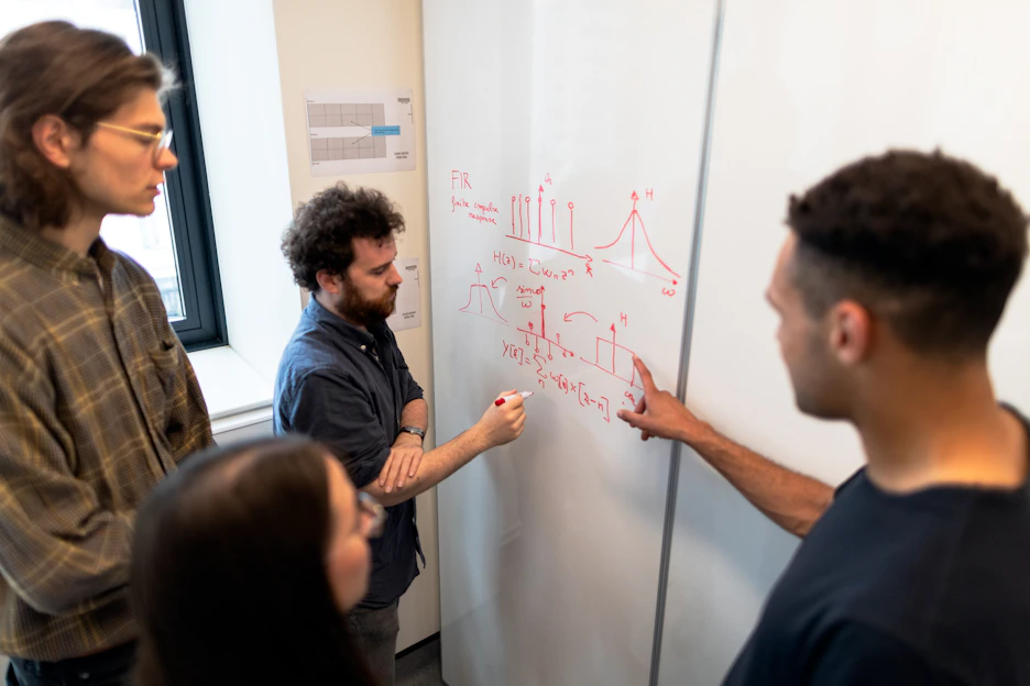 A focused teacher explaining a math problem on a whiteboard to attentive students.