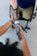 A close-up interaction between two individuals, focusing on one person fitting a prosthetic arm onto another's arm. The prosthetic is sleek and metallic, suggesting advanced technology. The scene suggests a sense of care and assistance.