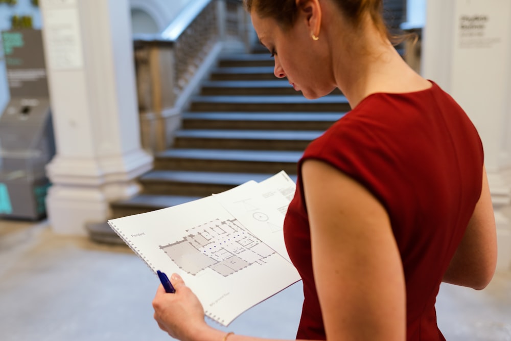 woman in red sleeveless shirt holding white printer paper