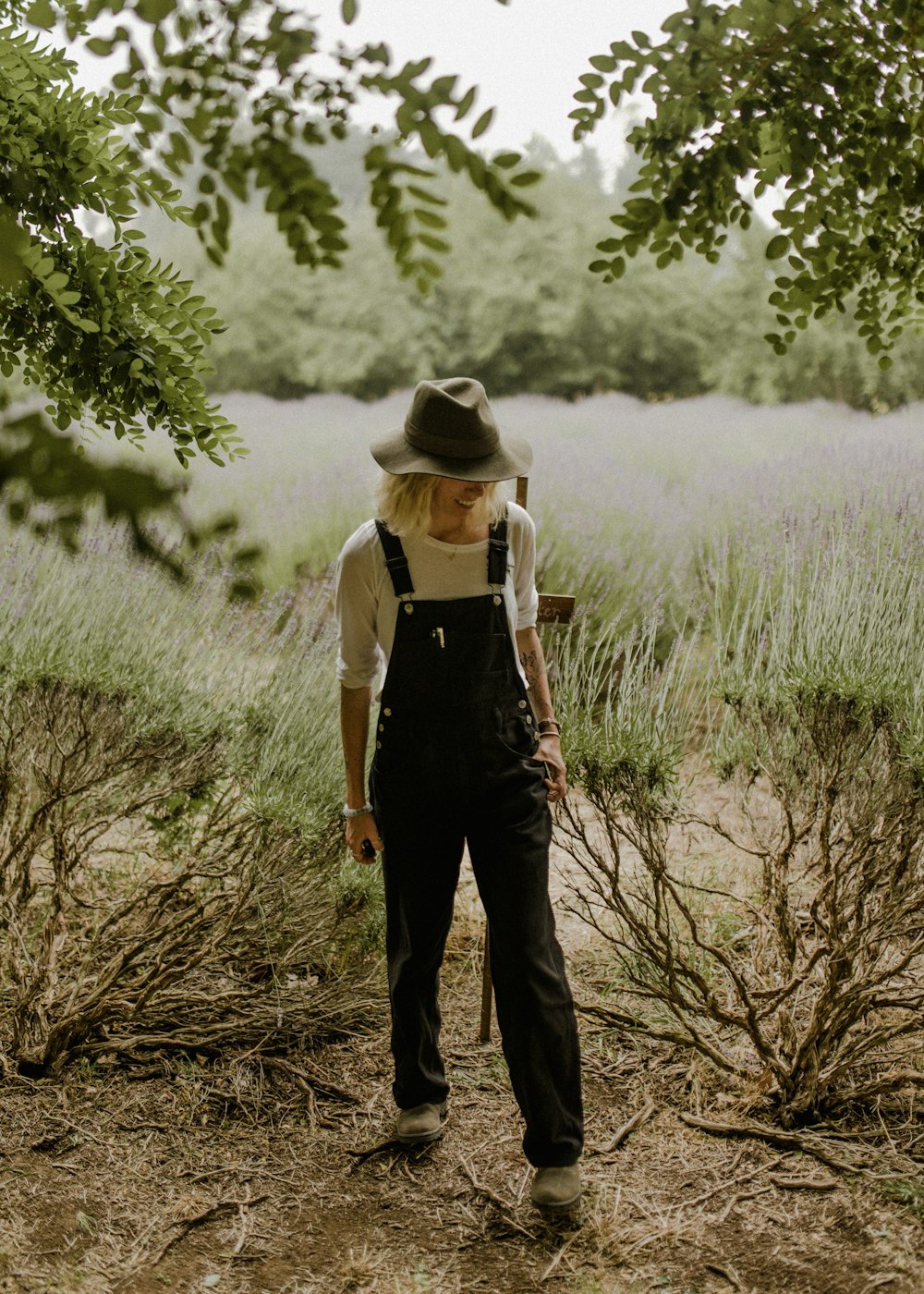 woman in white long sleeve shirt and black pants standing on brown wooden log during daytime