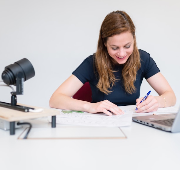 a woman sitting at a desk writing on a notebook