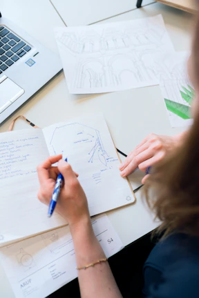 Close-up of hands collaborating over documents with a navy blue pen and notebook.