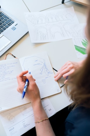 Close-up of a hand sketching a strategic plan on a notebook with a pen.