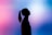 A silhouette of a person with a ponytail, facing upwards against a vibrant gradient background of pink and blue hues.