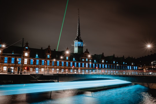 lighted building near body of water during night time in Copenhagen Denmark