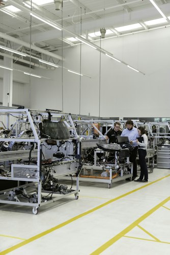 A factory worker examining a component closely under bright inspection lighting