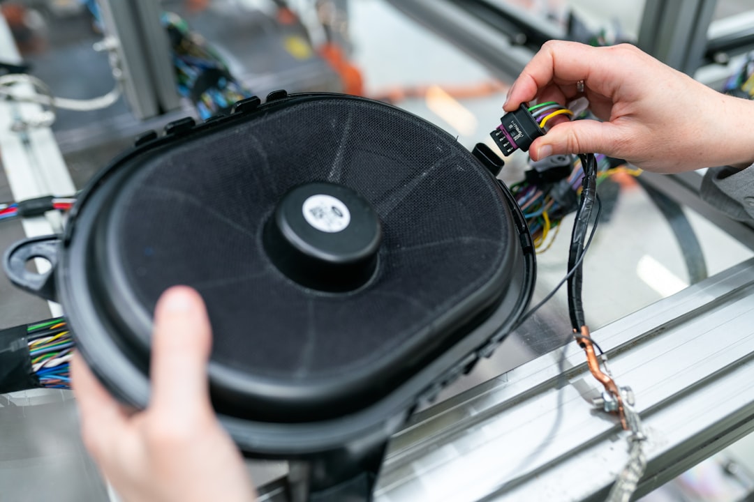 person holding black and yellow device, Female electronics engineer tests vehicle speaker