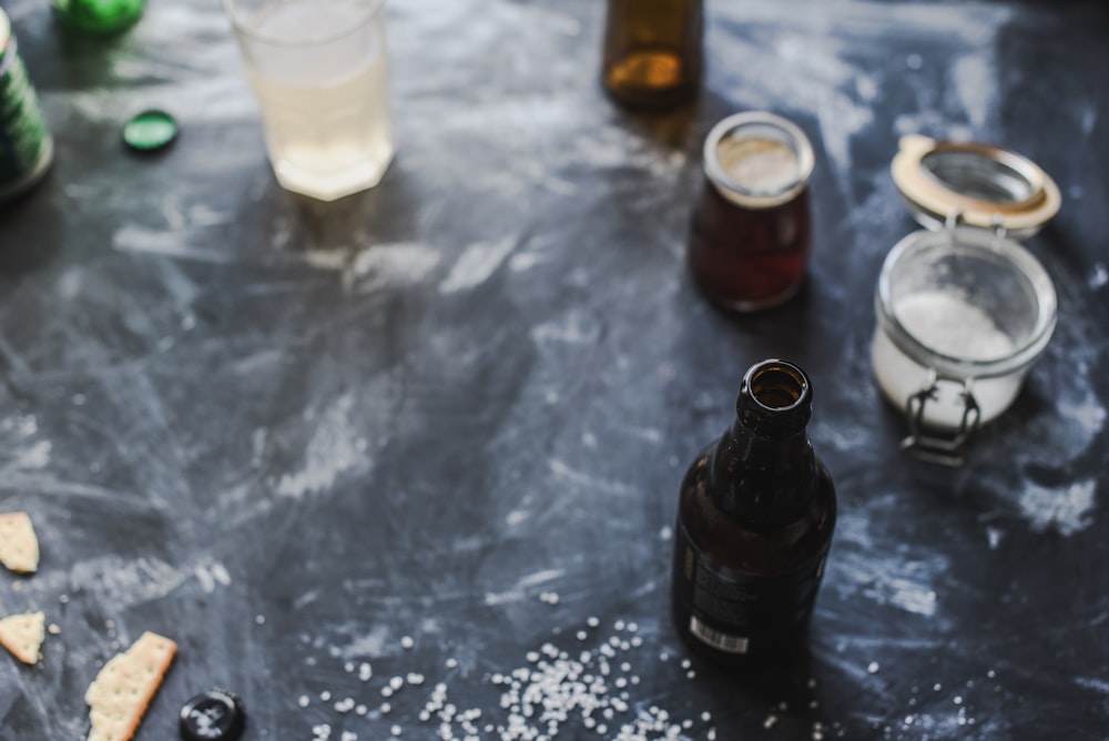 black glass bottle beside clear drinking glass