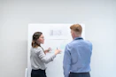 two colleagues discussing ideas at whiteboard
