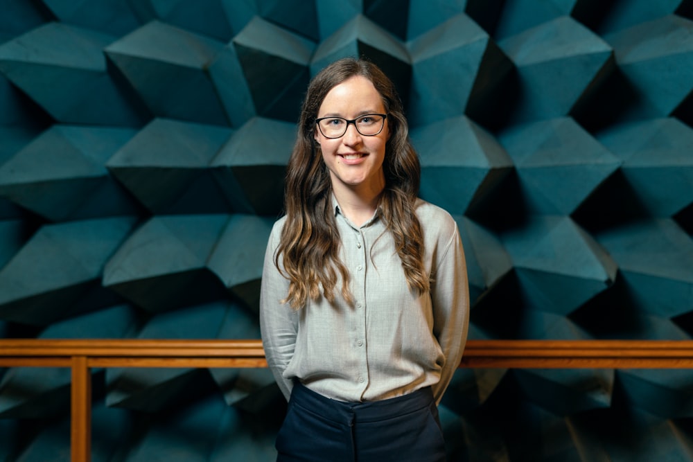 Femme en chemise blanche boutonnée et jean bleu portant des lunettes à monture noire