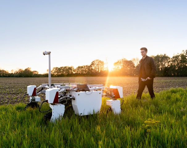 man in brown shirt standing on green grass field during sunset