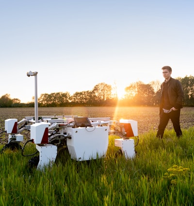 man in brown shirt standing on green grass field during sunset