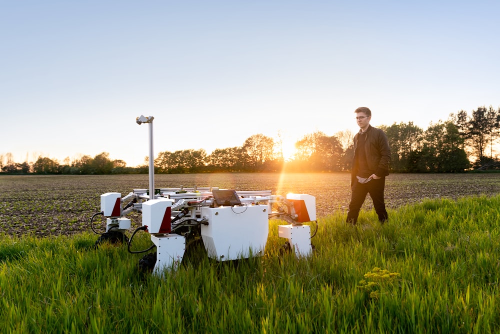 Mann im braunen Hemd steht während des Sonnenuntergangs auf grünem Grasfeld