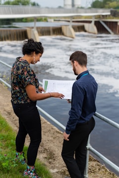 man in blue and red floral shirt and black pants standing on gray concrete pavement during