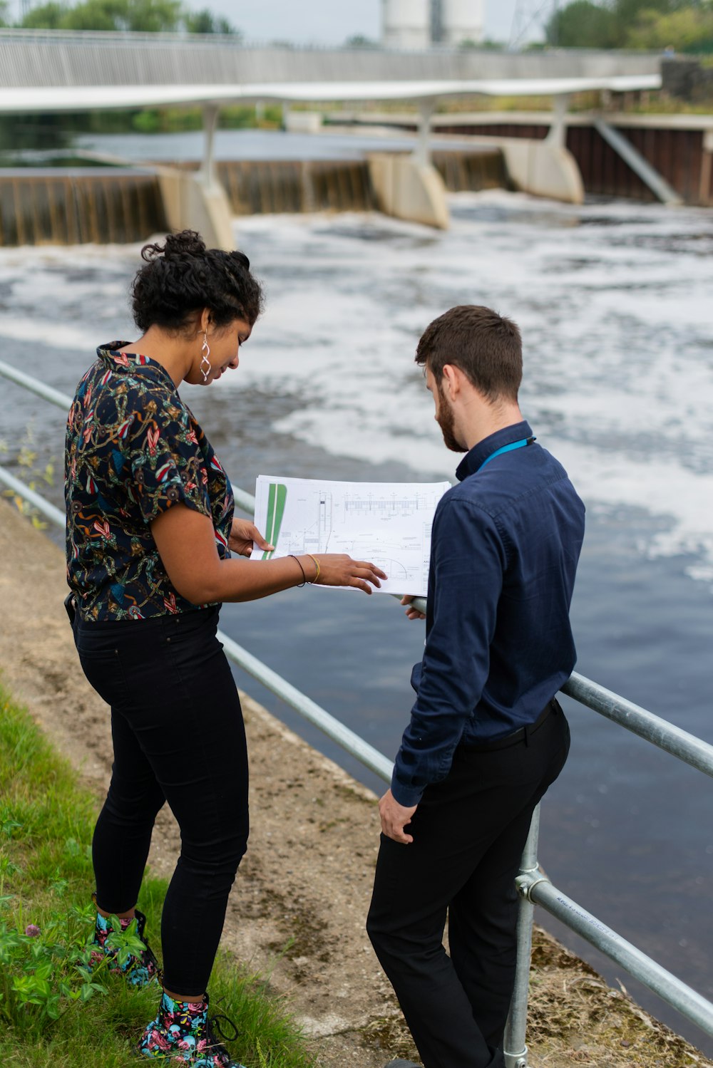 man in blue and red floral shirt and black pants standing on gray concrete pavement during