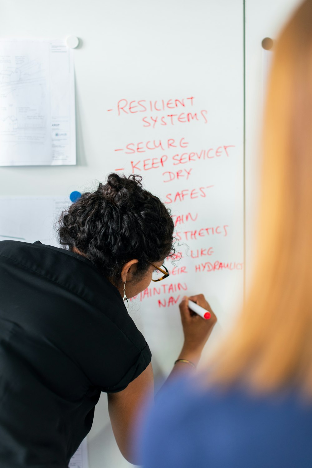 man in black shirt writing on white board