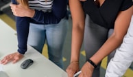 woman in black shirt and blue denim jeans writing on white paper