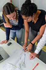 woman in black shirt and blue denim jeans writing on white paper