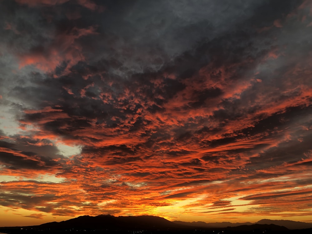 silhouette de montagne sous ciel nuageux au coucher du soleil