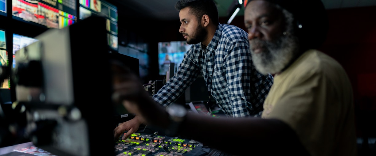 man in blue and white checkered button up shirt sitting beside man in yellow shirt