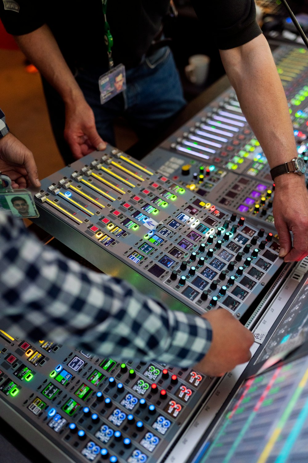 Person im grün-weiß karierten Langarmshirt spielt Audiomixer