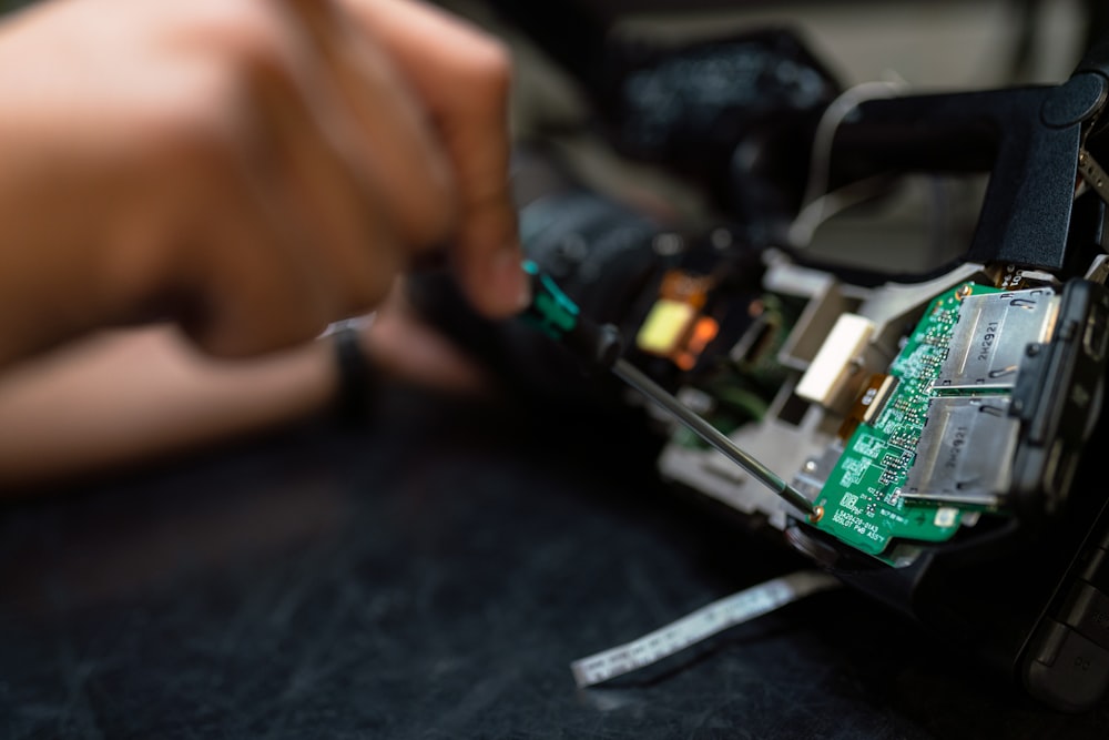 person holding green and black circuit board