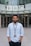 man in white button up shirt standing on sidewalk during daytime