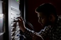 A person is concentrated on working with cables connected to a server rack in a dimly lit environment. The focus is on their hands and the server equipment, suggesting a technical task.