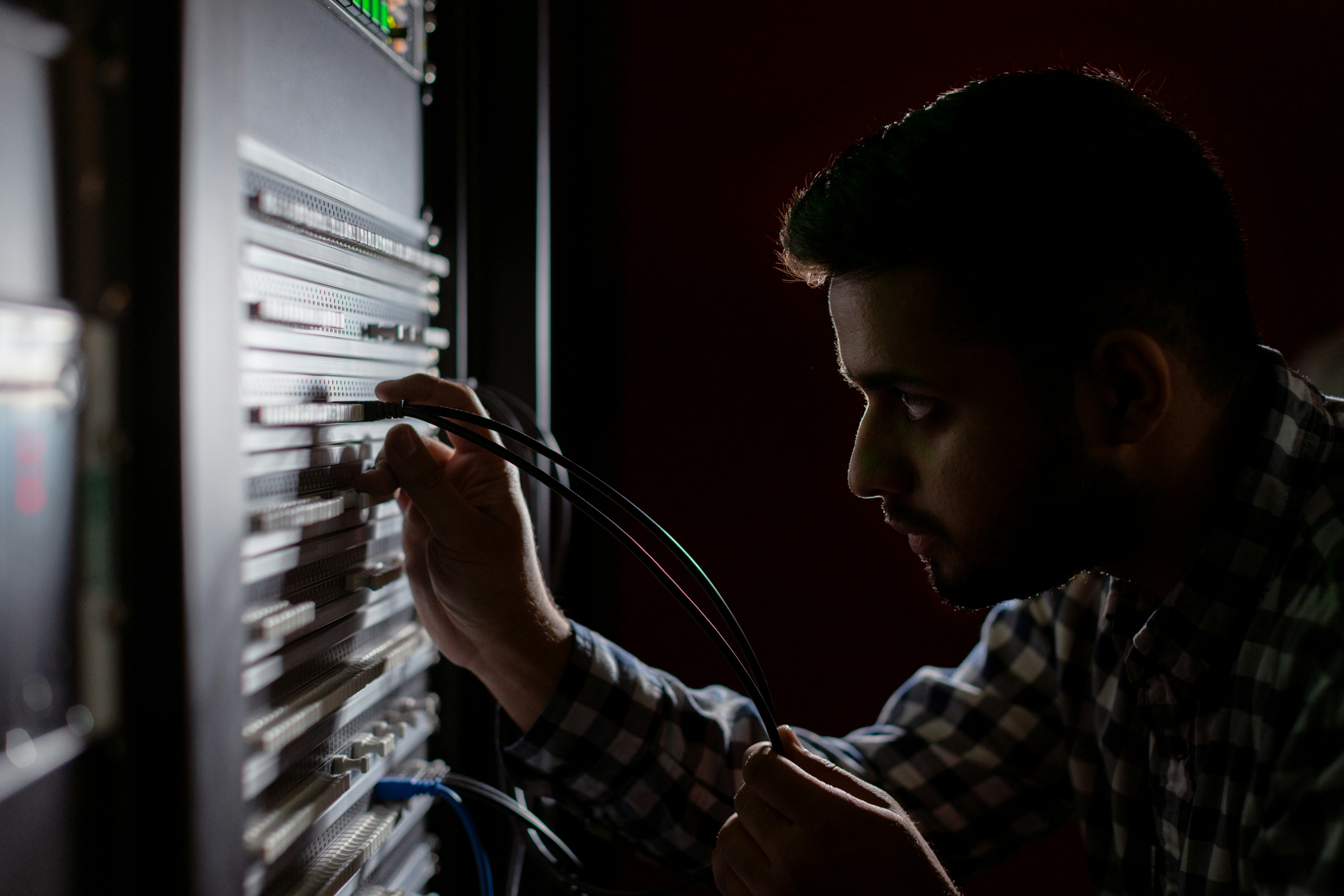 server room technician inspecting enterprise networking gear and fiber optic cables