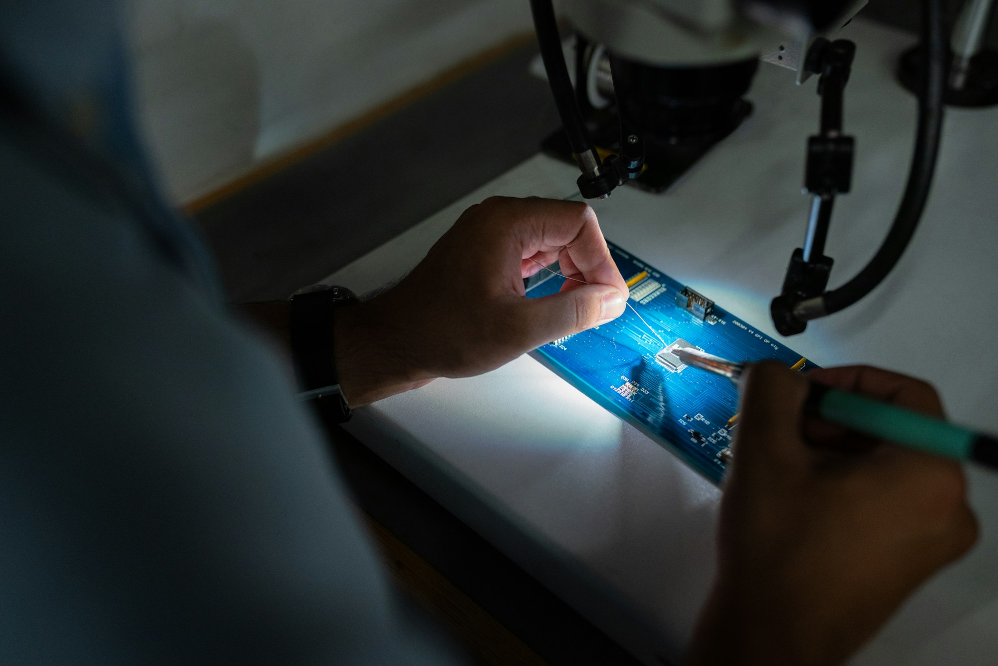 Male broadcast engineer solders circuit board