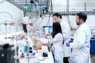 man in white chef suit standing in front of white and red plastic bottles chemistry teams background