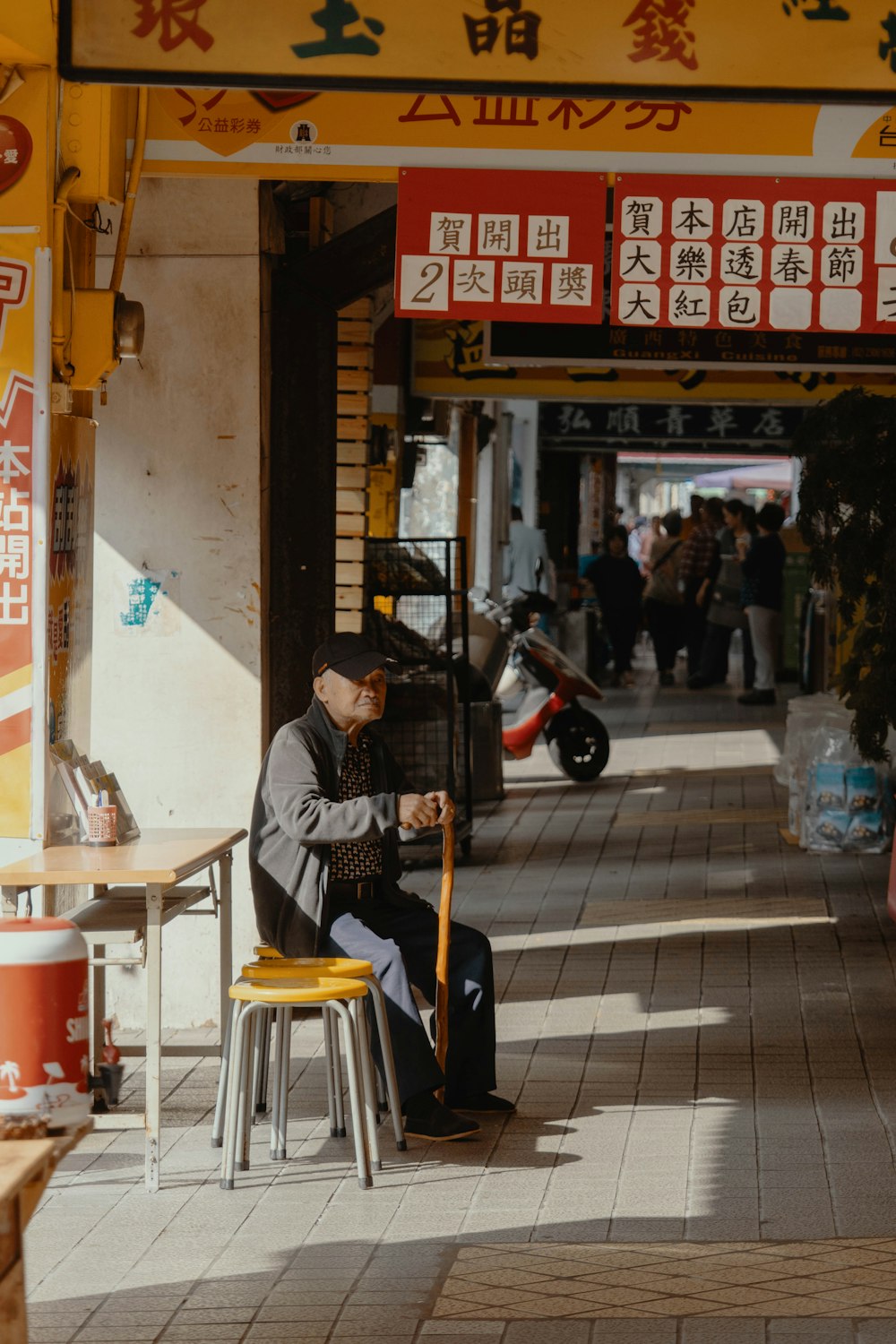 黄色い椅子に座る灰色のジャケットと黄色いズボンの男