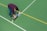 Close-up of a worker applying durable ground marking on a sports field under bright daylight.