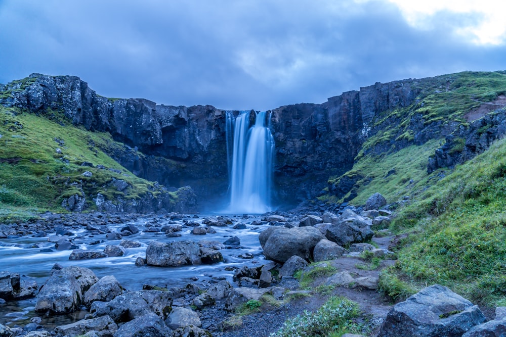 waterfalls on rocky mountain under cloudy sky during daytime