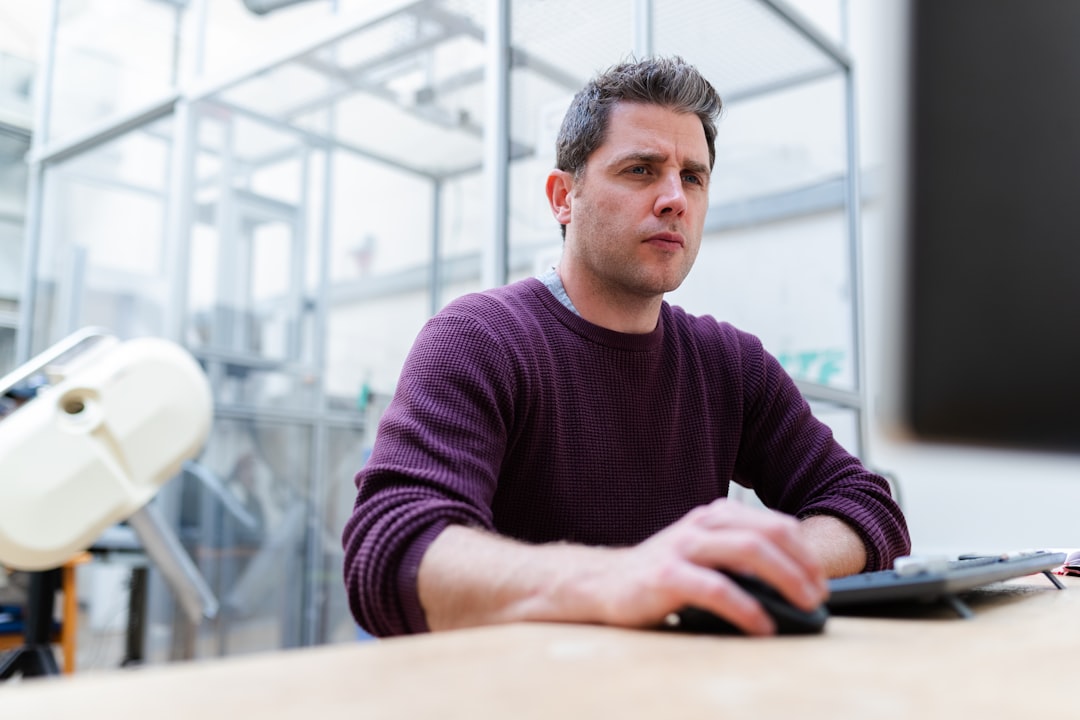 man in purple sweater sitting at the table, Male sports engineer on computer