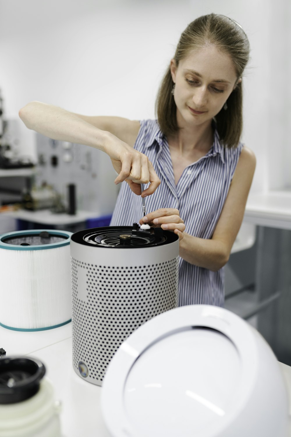 woman in white and black stripe tank top holding black and white round container