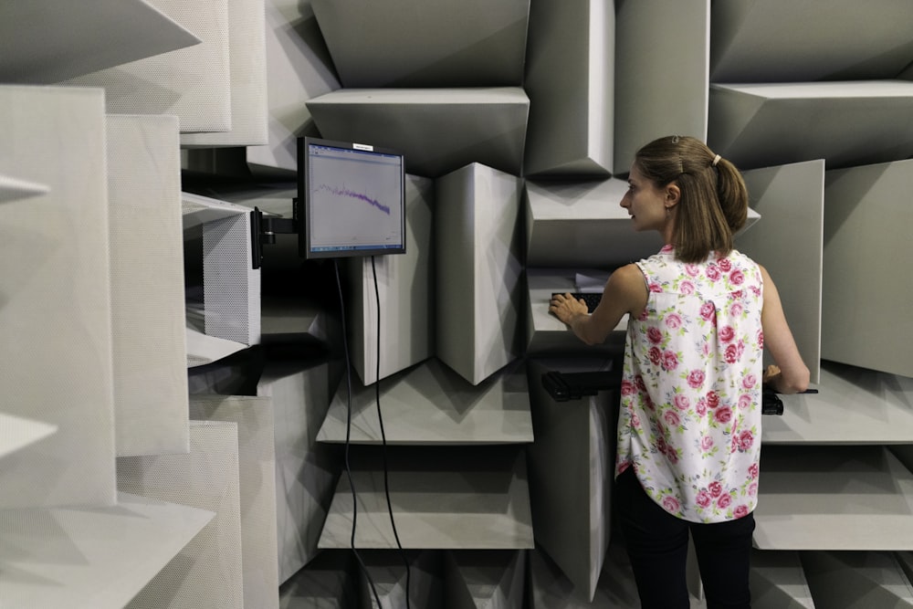 woman in white pink and green floral shirt standing beside gray flat screen tv