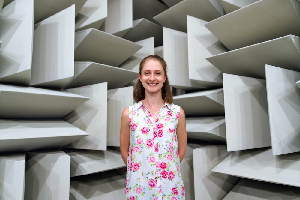 Frau in weißem und rosafarbenem ärmellosem Blumenkleid, das auf weißer Holztreppe steht