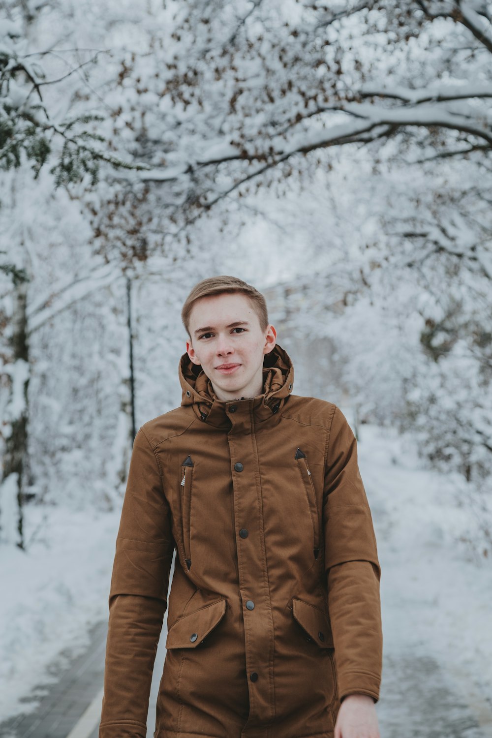 man in brown zip up jacket standing on snow covered ground during daytime