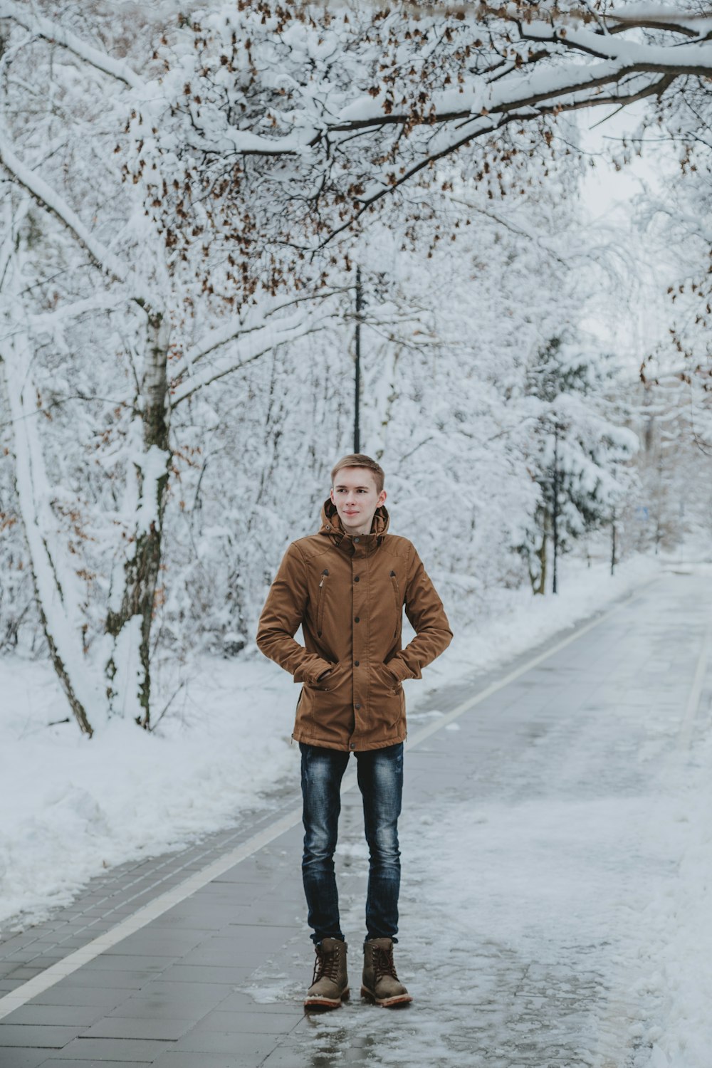 man in brown jacket standing on snow covered ground