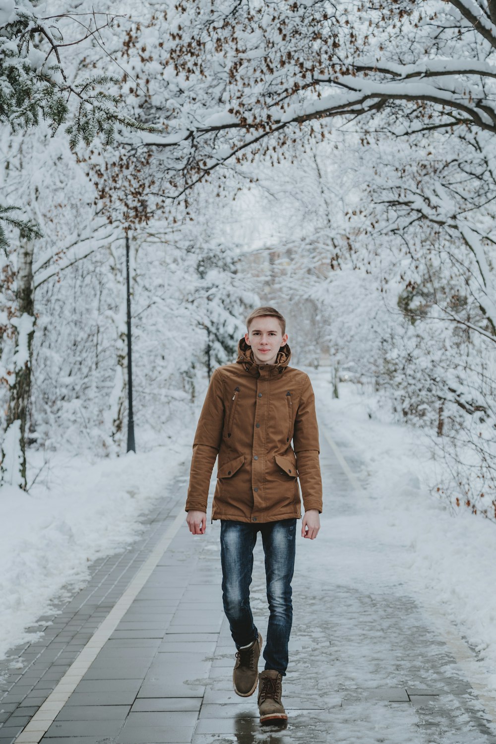 woman in brown turtleneck sweater and blue denim jeans standing on snow covered ground