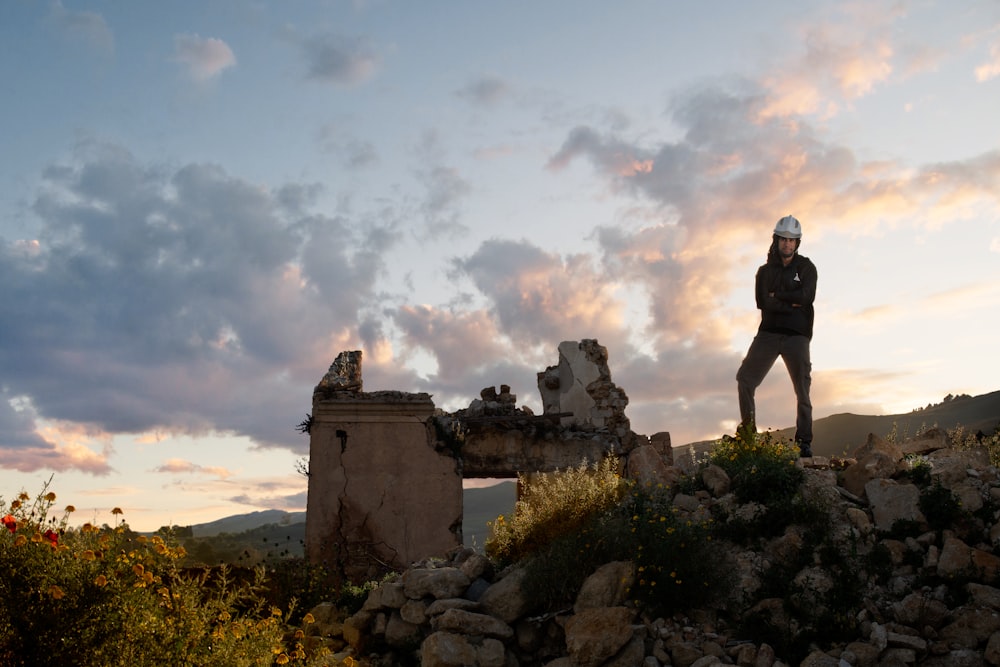 man standing on rock formation under cloudy sky during daytime