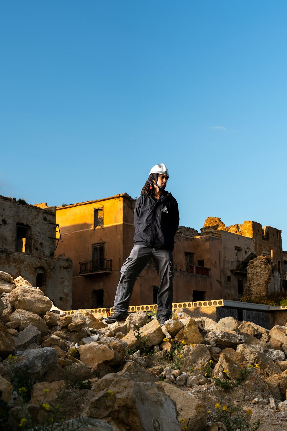 man in black jacket and blue denim jeans standing on rocky ground during daytime