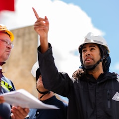 man in black jacket wearing yellow hard hat