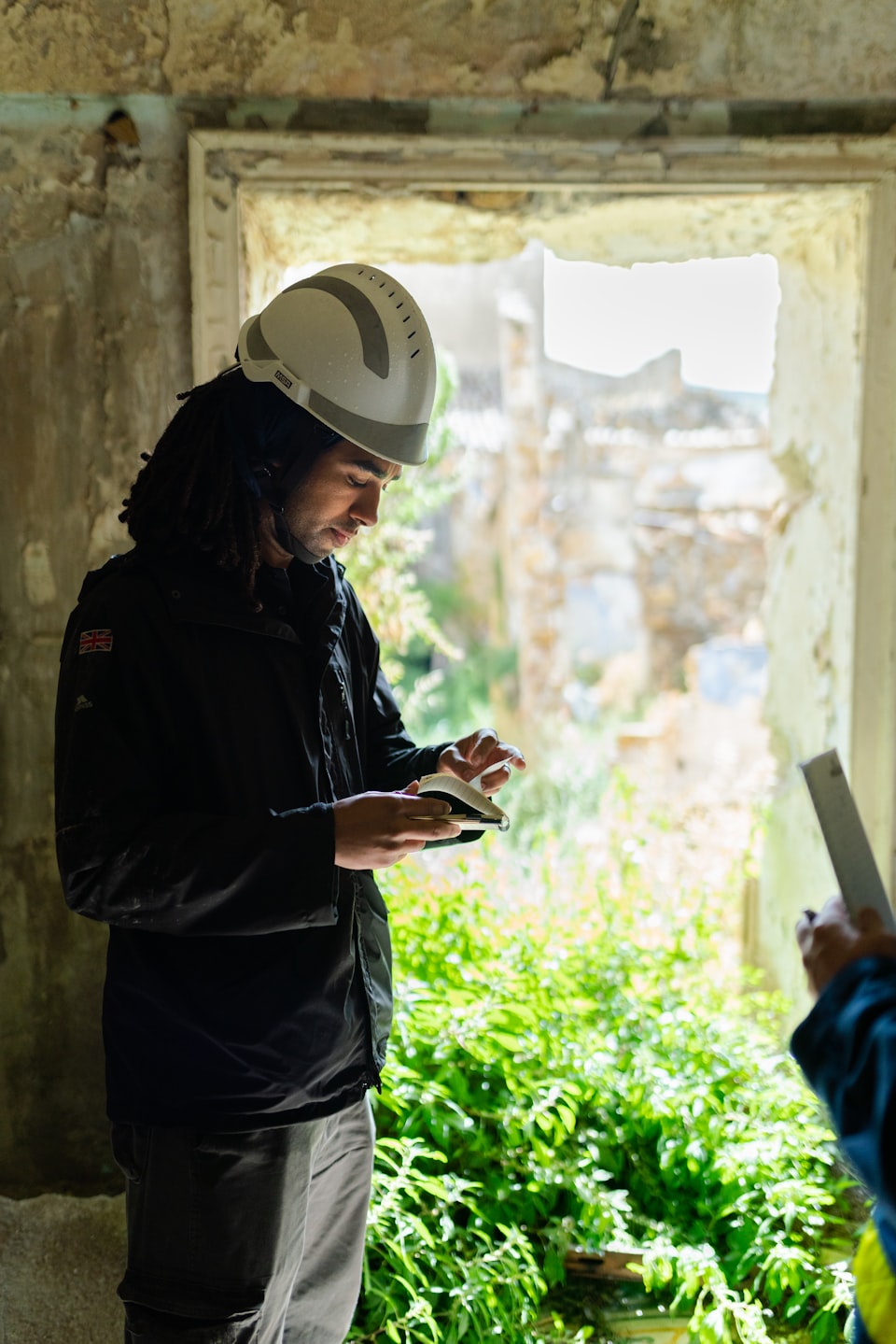 Contractor in a hard hat using a phone inside a house stripped back for a remodel