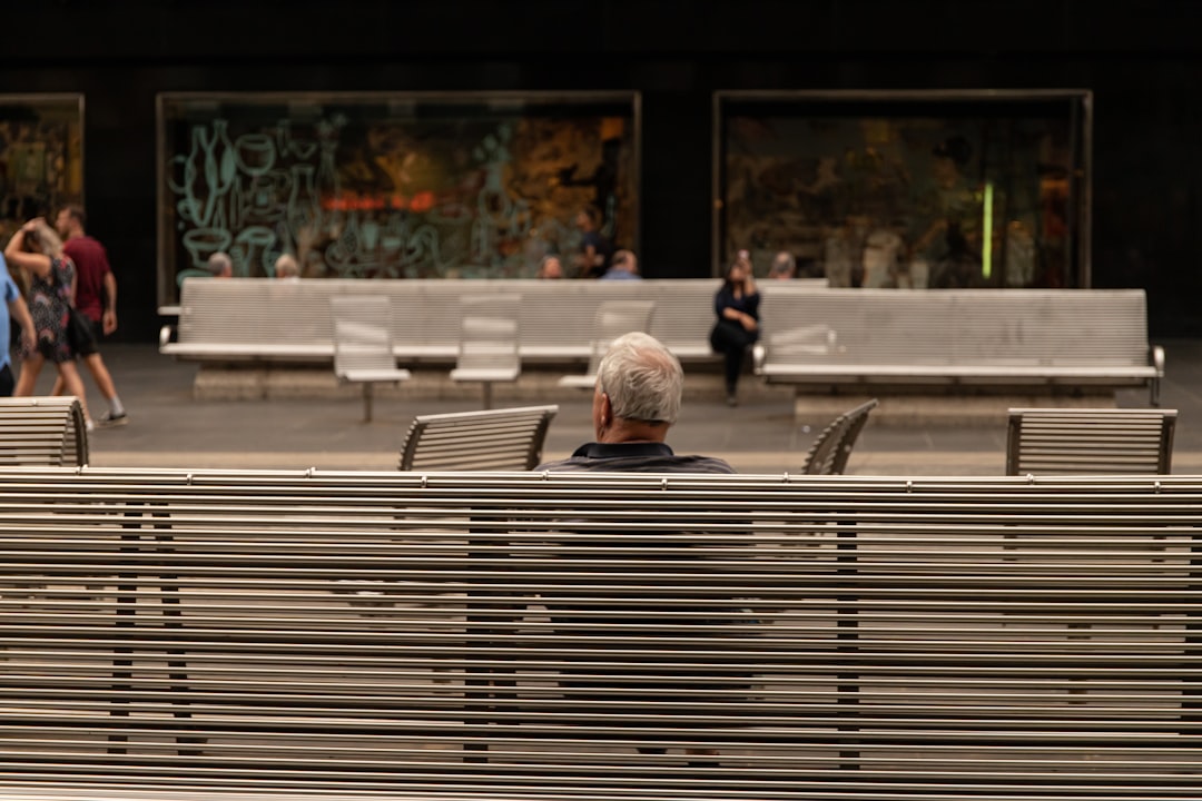 person in gray jacket sitting on bench during daytime