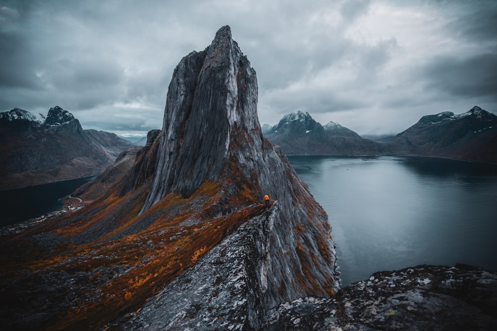 brown and gray rock formation near body of water under white clouds during daytime